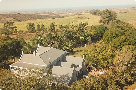 Aerial view of a farmhouse surrounded by trees, with farmland stretching to the horizon